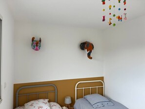 A bedroom with a bed, a nightstand, and a wall-mounted hanging toy.