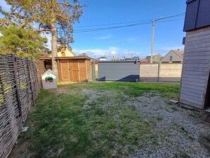 A residential backyard with a fenced area, a small shed, and a house.