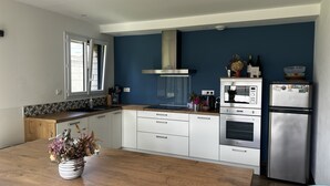 A modern kitchen with white cabinets, a wooden countertop, and stainless steel appliances. - La Villa Case-bi, Profitez en Famille de ce Magnifique Logement (Saint-Germain-sur-Ay)