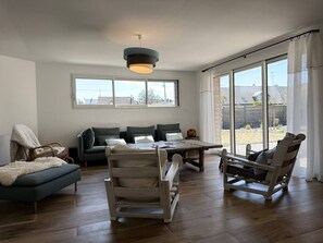 A spacious living area with a wooden floor, a sofa, a dining table, and a rocking chair.