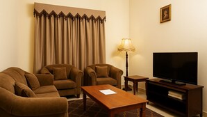 Un salon avec deux canapés, une table basse, un téléviseur, une lampe et un tableau au mur.