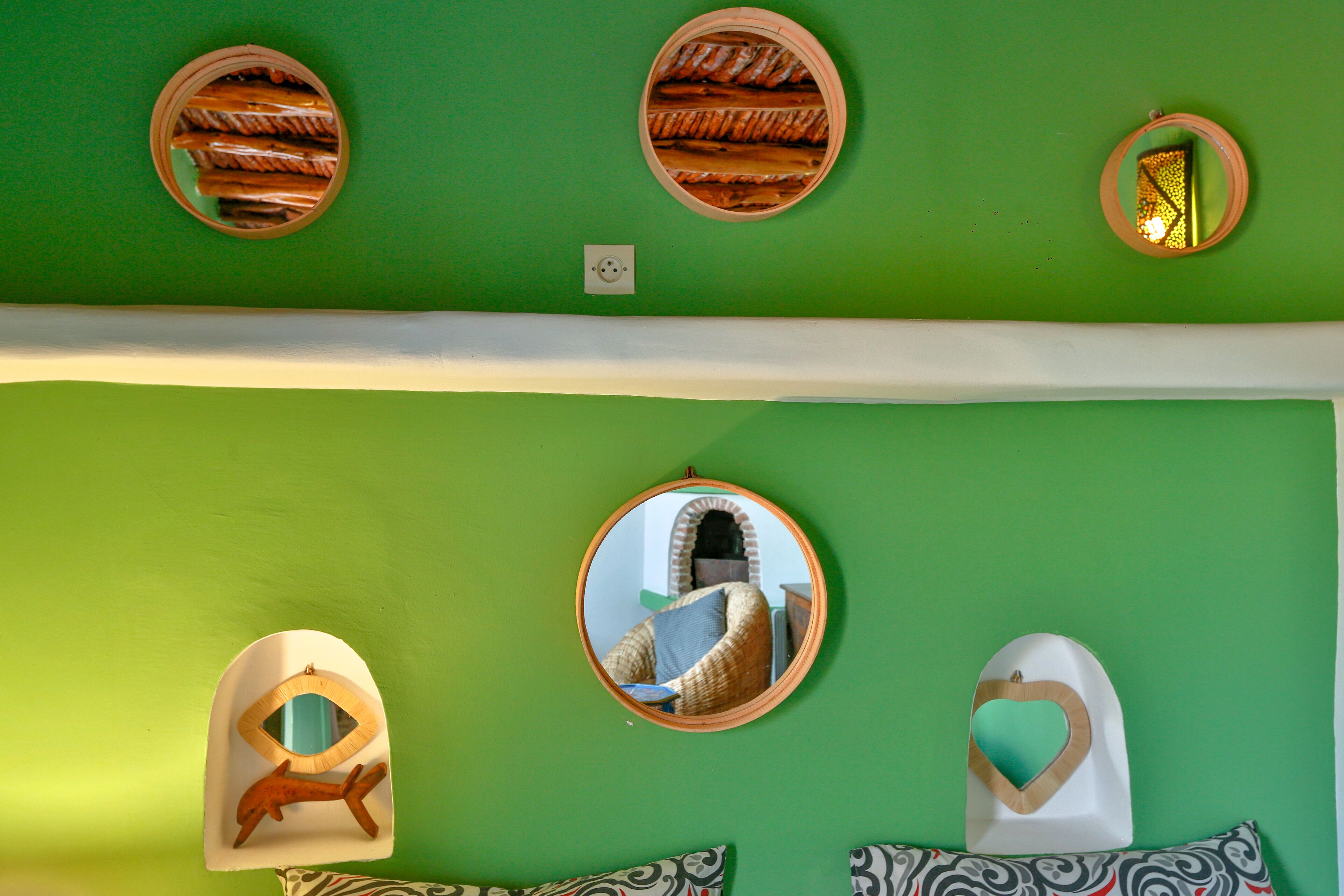 A room with green walls, multiple round mirrors, and decorative wall art.