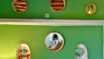 A room with green walls, multiple round mirrors, and decorative wall art.