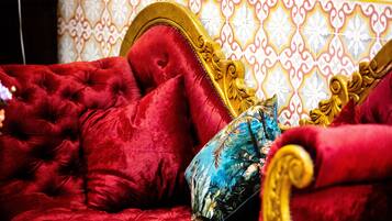A red upholstered bed with a gold headboard and ornate detailing, set against a patterned wall.