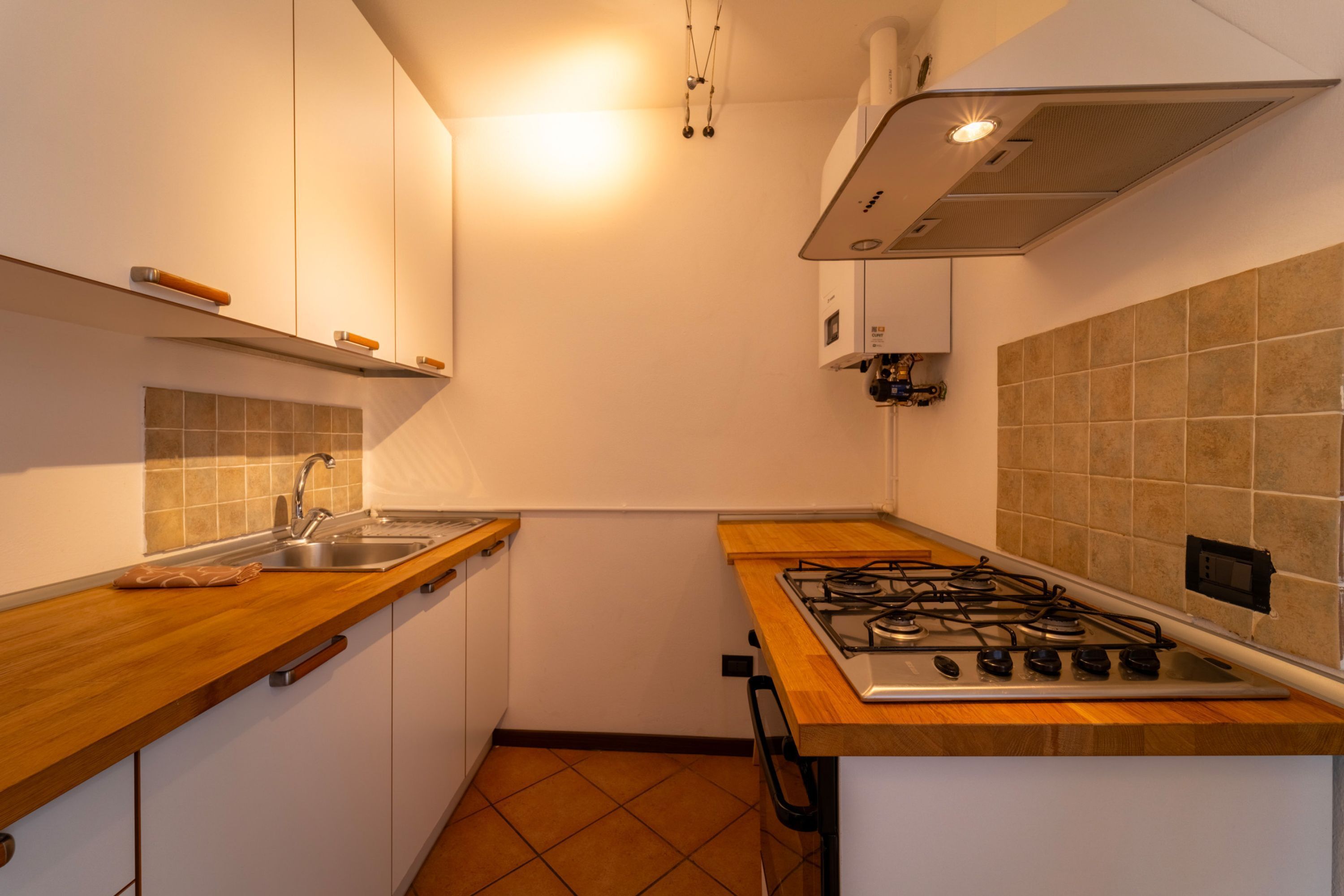 A compact kitchen with a gas stove, a sink, and wooden countertops.