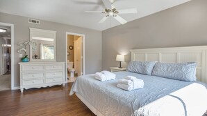 Un dormitorio con cama, mesita de noche, cómoda y ventilador de techo.