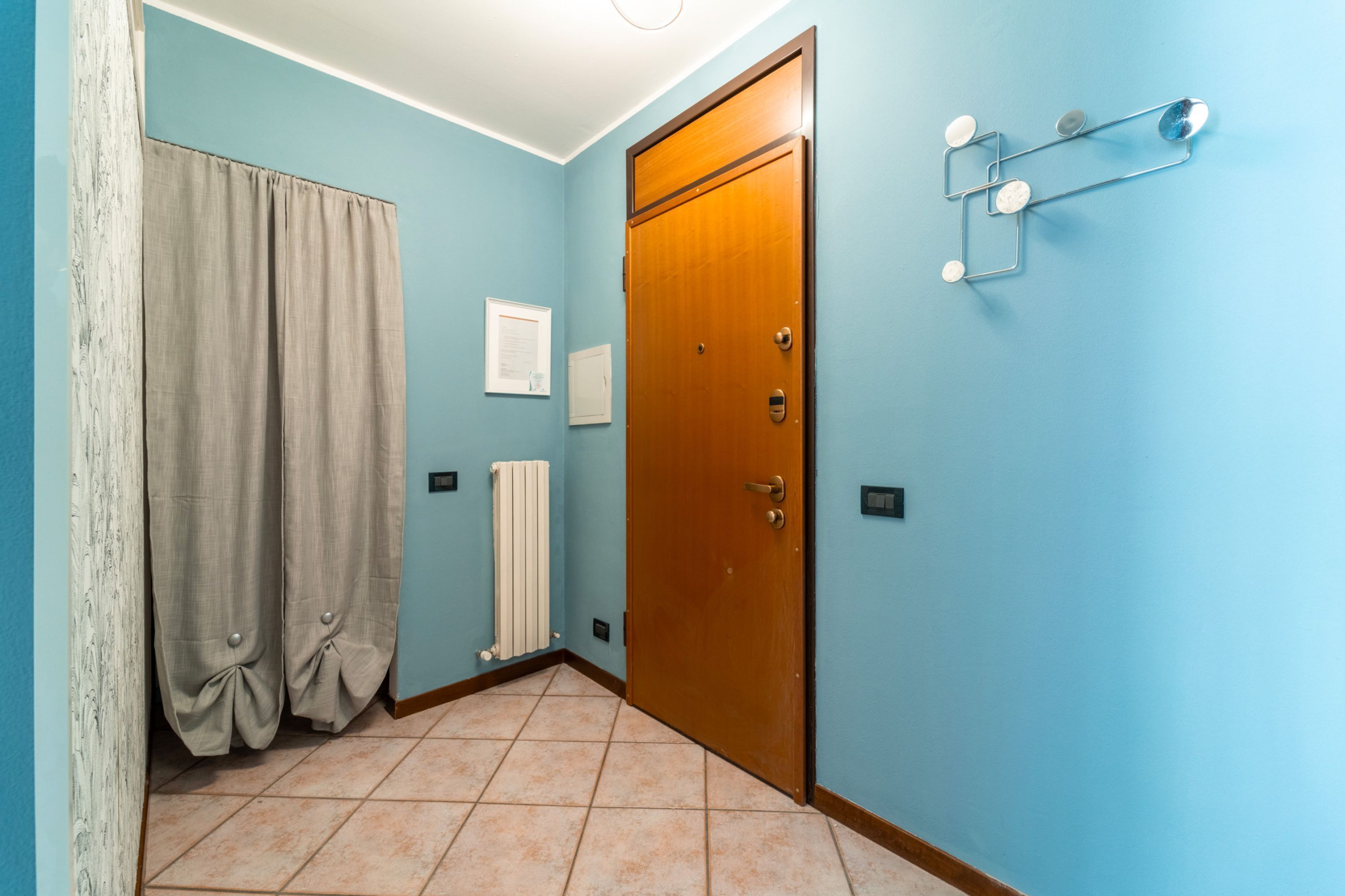 Ein Zimmer mit Holztür, hellblauen Wänden, einem Heizkörper und einem Vorhang.