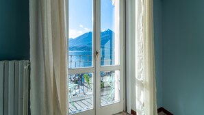 Ein Zimmer mit großem Fenster mit Blick auf einen See und Berge.