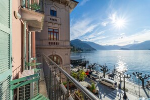 Ein Gebäude mit einem Balkon, der auf einen See und Berge im Hintergrund blickt, sowie einem Steg.