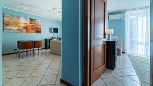 Ein modernes Hotelzimmer mit großem Fenster, einer Essecke mit Tisch und Stühlen, einem Flachbildfernseher und einem großen abstrakten Gemälde an der Wand.