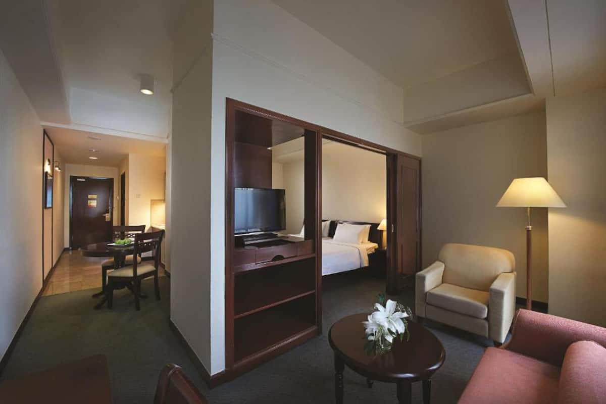A hotel room with a bed, a TV, a desk, a chair, and a lamp.