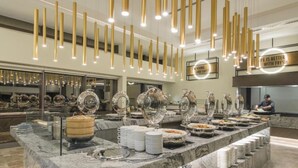 Een buffetopstelling met meerdere bedieningspunten, een marmeren aanrechtblad en hangende pendelverlichting.