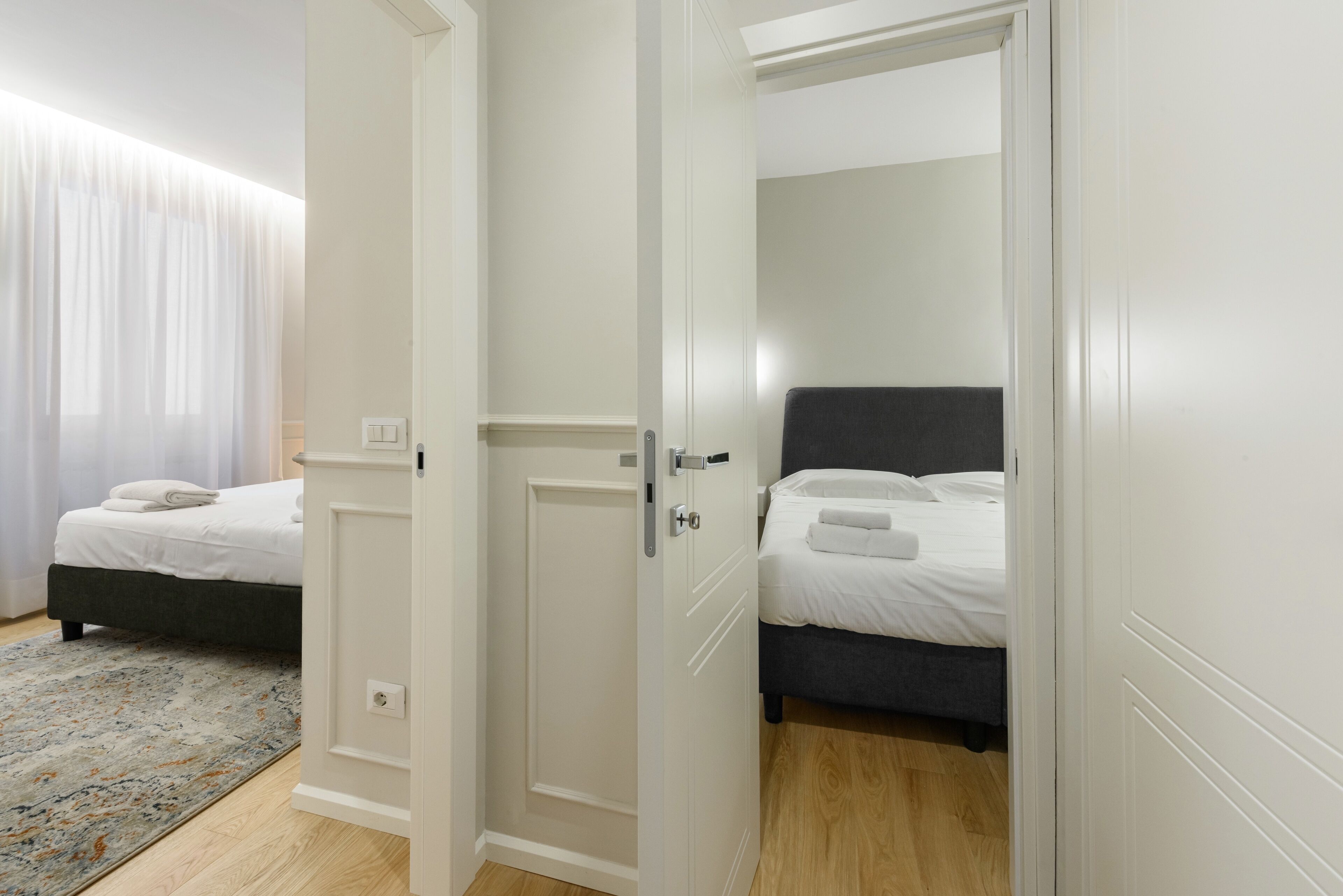 Une chambre avec deux lits, une porte blanche et un plancher en bois.