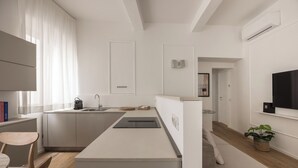 Una cocina moderna con isla integrada, un comedor con mesa y sillas de madera, y una sala de estar con sofá y televisor.