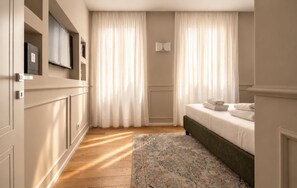 A bedroom with a bed, curtains, a rug, and a television on the wall. - Tornabuoni Place & Dream by Mmega (Florence)