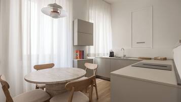 Una cocina moderna con una mesa redonda, sillas de madera y un horno empotrado.