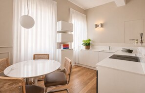 A modern kitchen with white cabinetry, a round dining table, and a hanging light fixture. - Tornabuoni Place & Dream by Mmega (Florence)