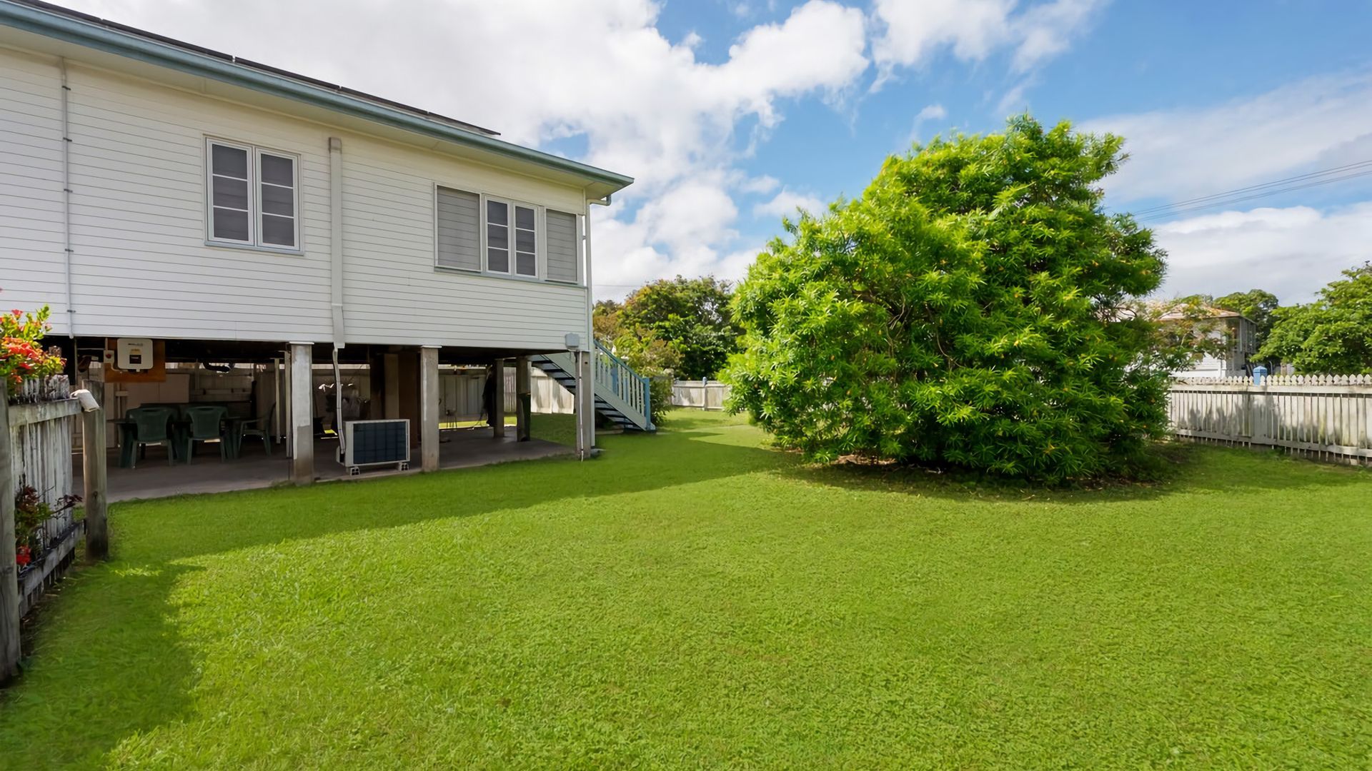 A two-story house with a covered patio area and a large tree in the backyard.