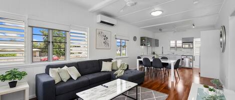 A modern living space with a dark sofa, a white coffee table, and a dining area with chairs.