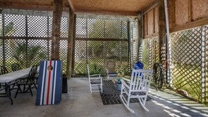Ein überdachter Patio-Bereich mit Tisch und Stühlen, einer Dekorationstafel und einem Spalier.