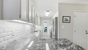 Eine Küche mit weißen Schränken, einer Marmorarbeitsplatte und einem Kühlschrank.