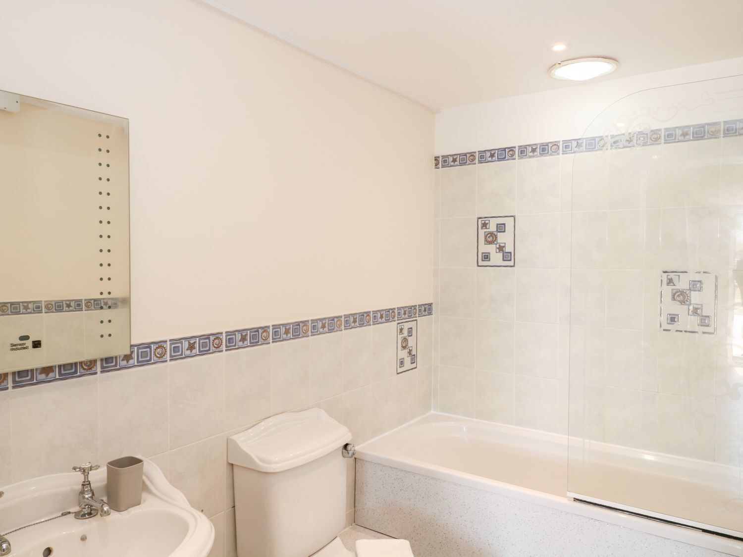 Un baño con bañera, inodoro, lavamanos y espejo.