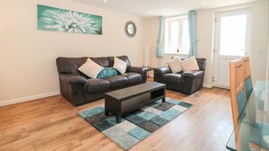 A living room with two leather sofas, a coffee table, and a glass table. - Emminster (Weymouth)