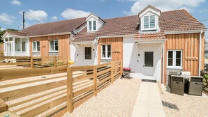 A row of wooden cottages with tiled roofs, a gravel path, and a wooden fence. - Emminster (Weymouth)