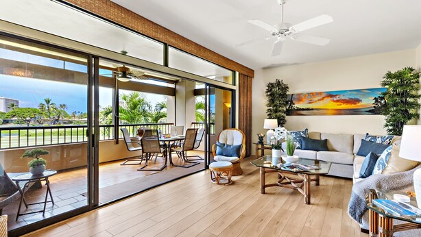 A spacious living area with a balcony, large windows, and a ceiling fan.