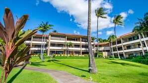 A hotel with a central courtyard, palm trees, and a clear blue sky.