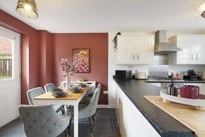 Una cucina moderna con armadietti bianchi, un'area pranzo con tavolo apparecchiato per due e vista sullo spazio abitativo adiacente.