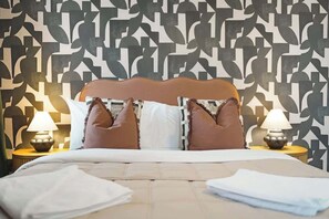 Un letto con testiera in legno, due lampade sui comodini e una parete decorata.