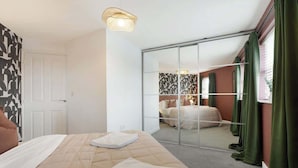 Een hotelkamer met een bed, een spiegel, een schuifdeur en een lamp.