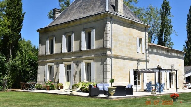 A stone building with a symmetrical facade, large windows, and a covered outdoor seating area. - Coin de Paradis en Bord de Dordogne 2 (La Riviere)