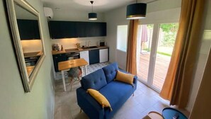 A compact living space with a kitchenette, a sofa, a dining table, and a small side table. - Coin de Paradis en Bord de Dordogne 2 (La Riviere)