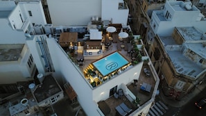 Vue aérienne d’un toit-terrasse avec une piscine, un espace salon extérieur et un bar.