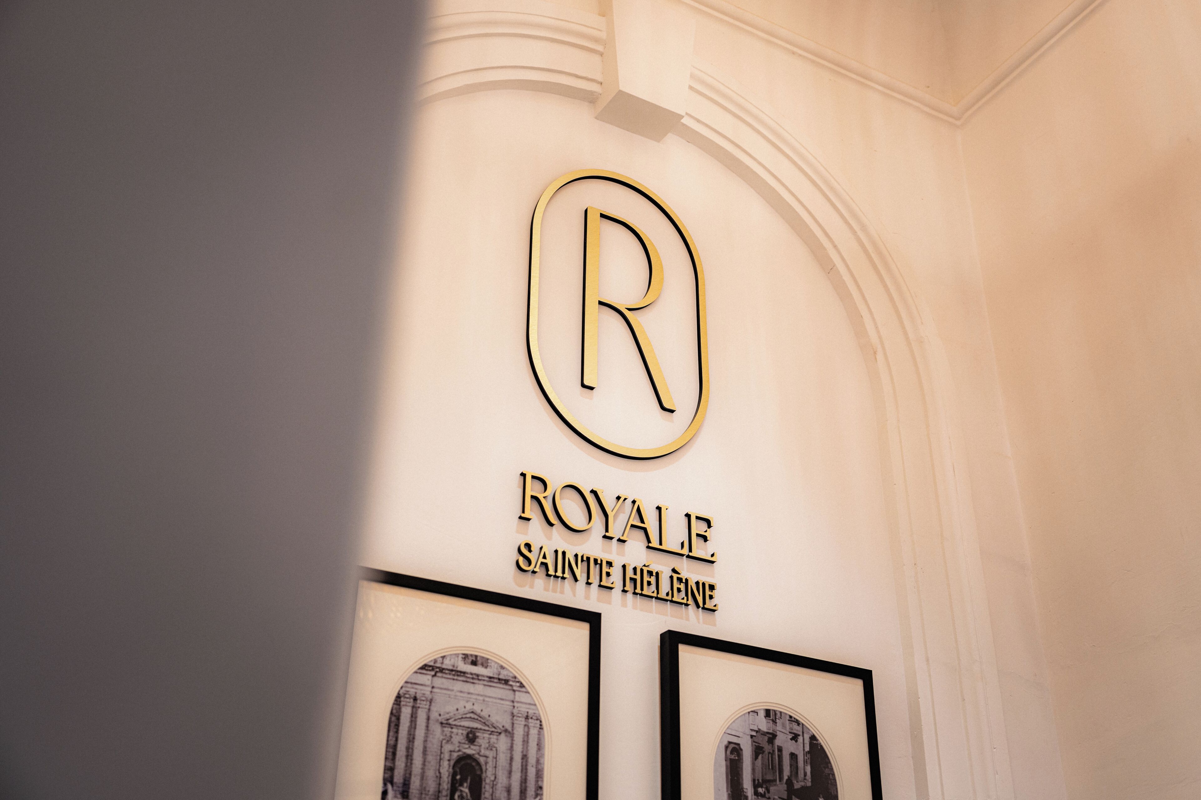 Una pared con el logotipo de una letra 'R' dorada y las palabras 'ROYAL' y 'SAINTE HÉLÈNE' debajo.