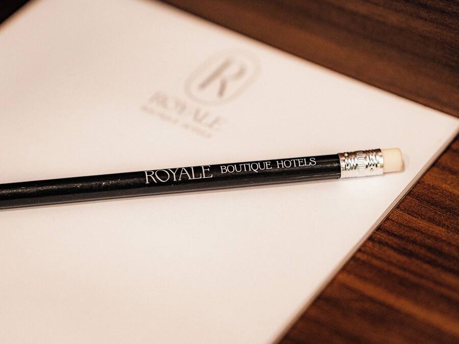 Un lápiz negro con el texto 'ROYALLE BOUTIQUE HOTELS', sobre una hoja de papel blanco con un logotipo.