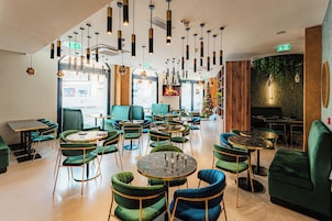 A modern interior with multiple seating areas, including round tables and chairs, and a visible exit sign.