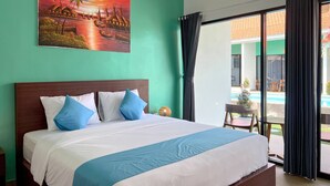 Habitación de hotel con cama, un cuadro de una escena tropical y vistas a una piscina a través de amplias ventanas.