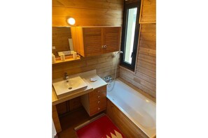 A wooden cabin bathroom with a sink, vanity, and bathtub.