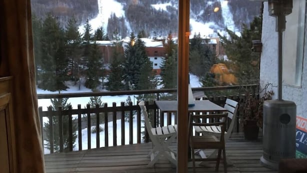 A balcony with a view of snow-covered mountains and trees.