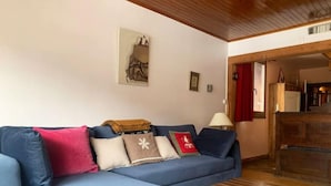 A living room with a blue sofa, a wooden coffee table, and a painting on the wall.