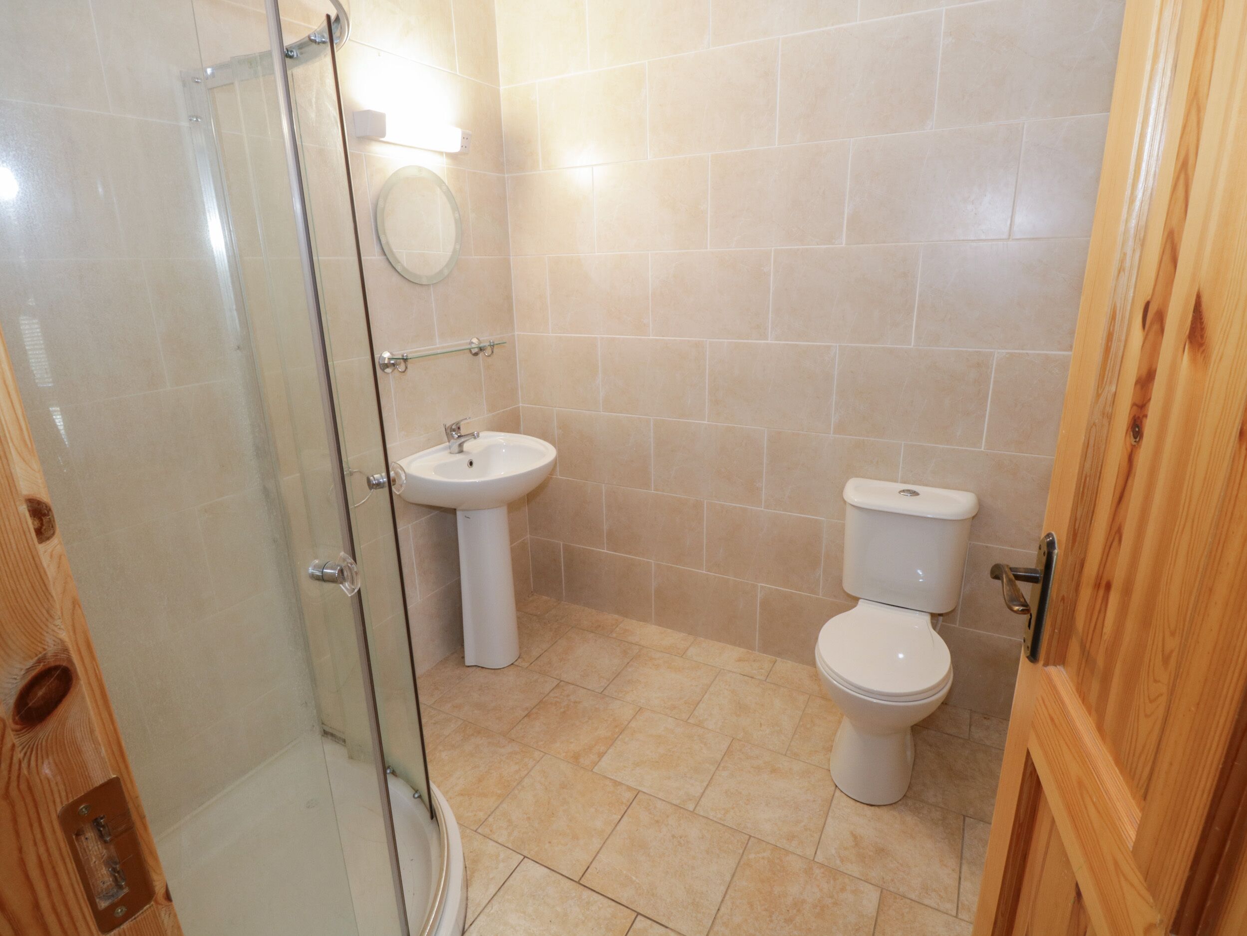Een badkamer met een douchecabine van glas, een wastafel en een toilet.