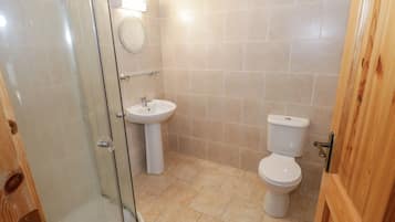 Een badkamer met een douchecabine van glas, een wastafel en een toilet.