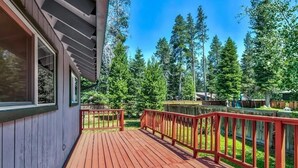 A wooden deck with red railings, surrounded by a forested area.
