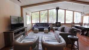 A spacious living room with a large window, a fireplace, a television, and a dining area.