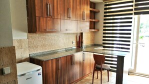 Cozinha com armários de madeira, painel de azulejos, bancada de granito e forno embutido.