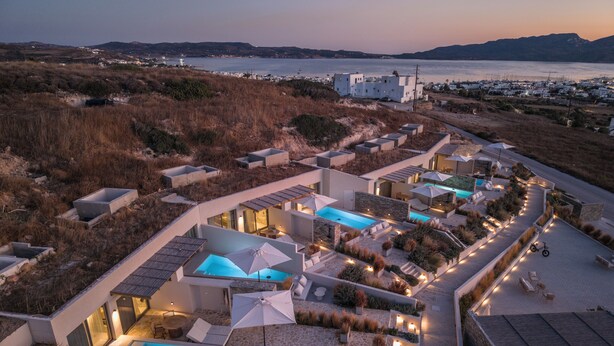A resort with multiple swimming pools, outdoor seating areas, and a view of the sea. - Solus Suites (Milos)