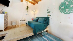 A cozy bedroom with a bed, a small table, a cabinet, and a hanging plant. - Cod Citra 008031-lt-1216 Affitto Pittoresca Casina Indipendente con Giardino (Imperia)